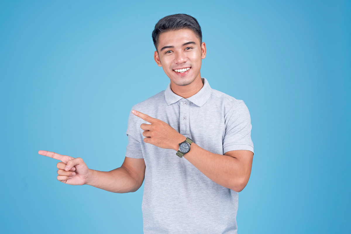 Man Gesturing and Pointing to the Left on Blue Background